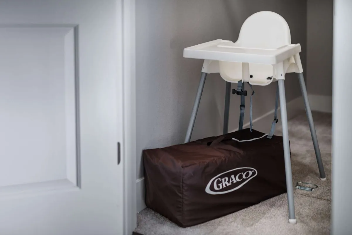 This image shows a bright, homey feeding area with a high chair set up next to a storage bag, suggesting comfort and convenience for families with young children. The setting is practical, clean, and welcoming, indicating thoughtful accommodation for little ones' needs.