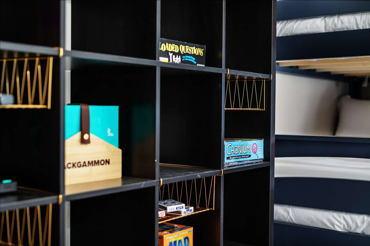 A playful upstairs space featuring a game shelf stocked with board games and a set of bunk beds, designed for older kids to relax, play, and socialize. The room feels fun and welcoming, with plenty of activities for memorable family moments.