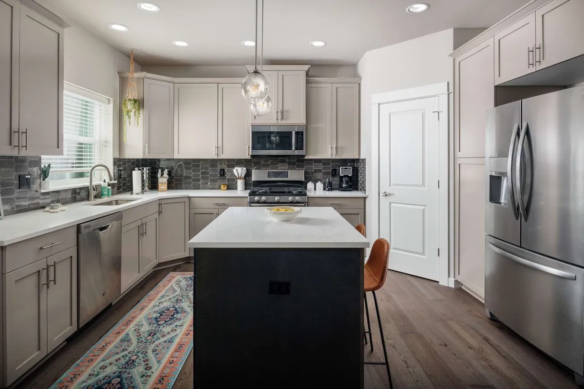 A modern kitchen with a central island, stainless steel appliances, and inviting lighting. The kitchen stands ready for cooking, entertaining, and shared meals, with plenty of space for everyone to gather around.