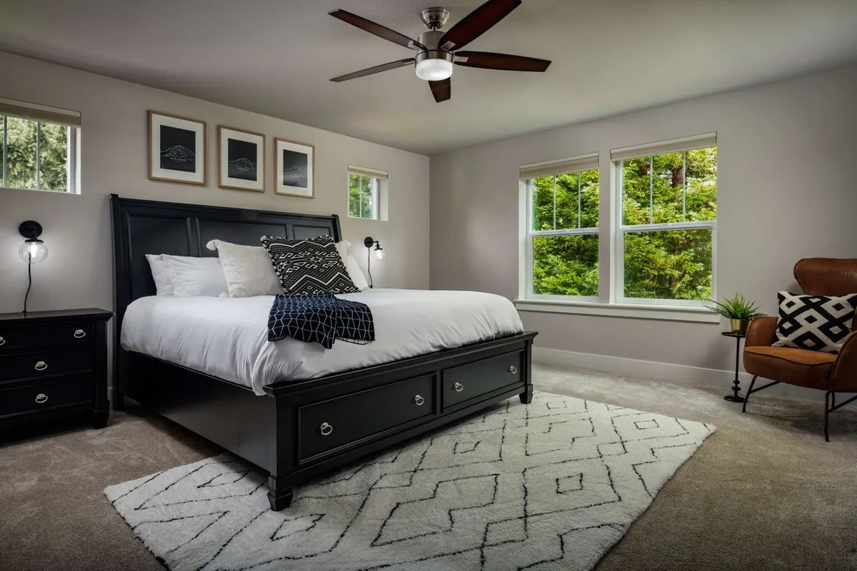 A tranquil bedroom featuring a large, inviting bed, an armchair by the window, soft natural light streaming in, and thoughtful decorative touches like a plush rug and framed artwork. The space exudes serenity and comfort, ideal for restful nights.
