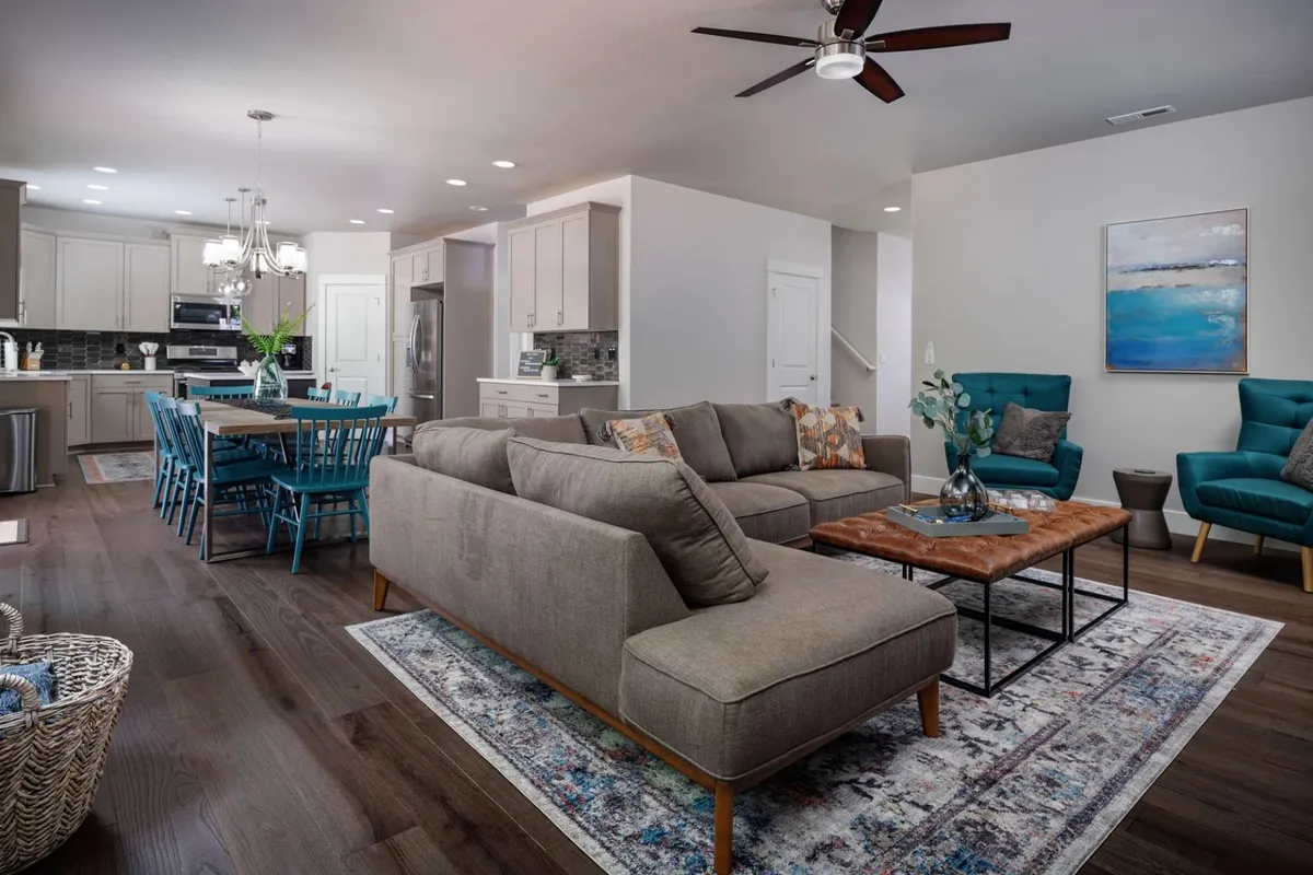 A cozy interior scene with a sofa, dining table, blue chairs, and artwork, bathed in natural light. The room is spacious and inviting, perfect for families relaxing together with their pets after a day outside.